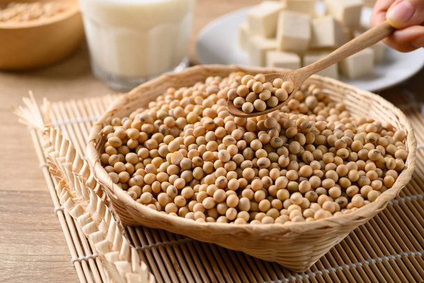 Graines de soja sèches dans un panier en bambou avec cuillère, tofu et lait de soja. Aliments végétaliens sains - Photo, image