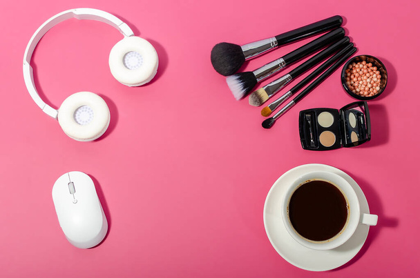 Female fashion beauty blogger home office workspace. Keyboard mouse, headphones, cosmetics, brush, coffee cup on pink red background. Flat lay, top view copy space. - Foto, Imagen