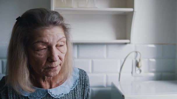 Triste vecchia donna dai capelli grigi che guarda attraverso la finestra. Persona vulnerabile in quarantena - Filmati, video