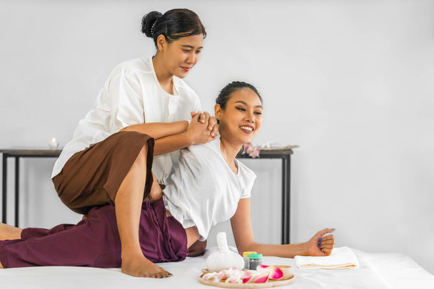 Young asian pretty woman has Thai massage therapy by professional Thai massage therapist of shoulder stretching - Foto, Imagen