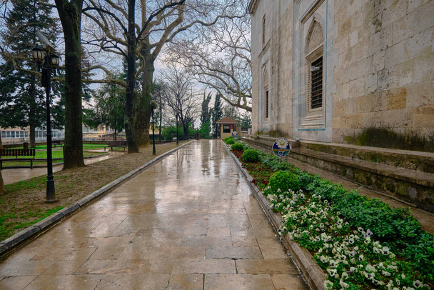 Dia chuvoso em Bursa na mesquita verde (yesil cami) e maneira coberta por grama verde feita de mármore e reflexão de árvores na poça existente no caminho de caminhada perto da mesquita. - Foto, Imagem