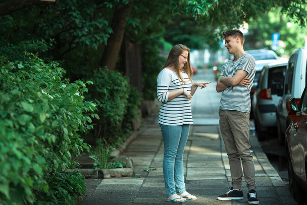 Két tinédzser fiú és lány beszélget az utcán.. - Fotó, kép