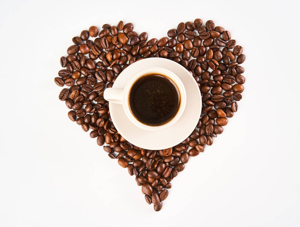 A cup of coffee inside a heart made out of coffee beans, isolated on white background - Foto, imagen