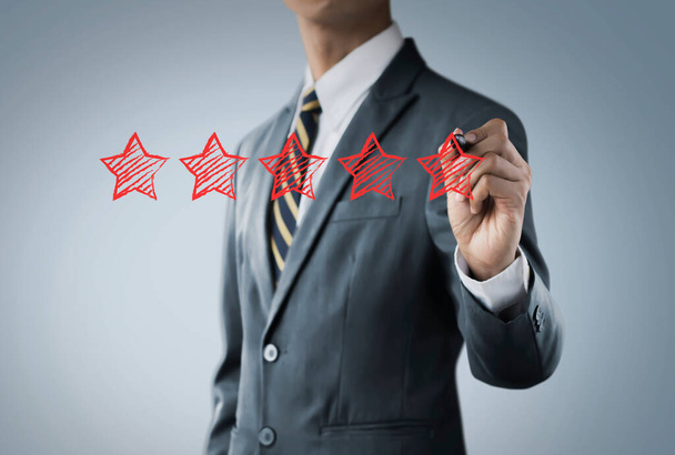 Підвищити рейтинг, ранжування, огляд, оцінку або концепцію класифікації. Бізнесмен малює п'ять червоних зірок, щоб підвищити рейтинг свого бізнесу на яскравому тлі
. - Фото, зображення