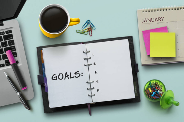 New Year goals, resolution or action plan concept. Notebook on table with laptop, calendar, coffee, plant and stationery. Flat lay (top view) notepad for input copy or text on turquoise background. - Photo, Image