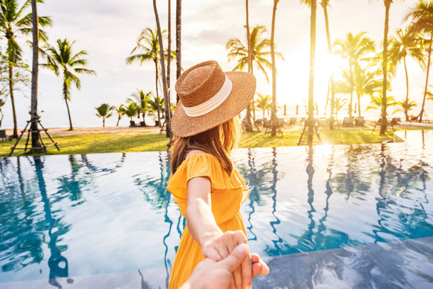 Junge Paare entspannen sich und genießen den Sonnenuntergang am Pool eines tropischen Resorts, während sie für den Sommerurlaub reisen - Foto, Bild