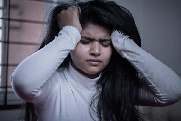 Muchacha milenaria estresada sosteniendo la cabeza cerrando los ojos debido al dolor o dolor de cabeza - Concepto de insomnio y trastorno mental. - Foto, Imagen