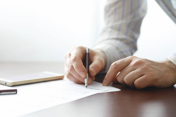 Επαγγελματική συνάντηση. Ένας άντρας υπογράφει συμβόλαιο. Άνδρας χέρι με στυλό κάνει σημειώσεις στο γραφείο. - Φωτογραφία, εικόνα