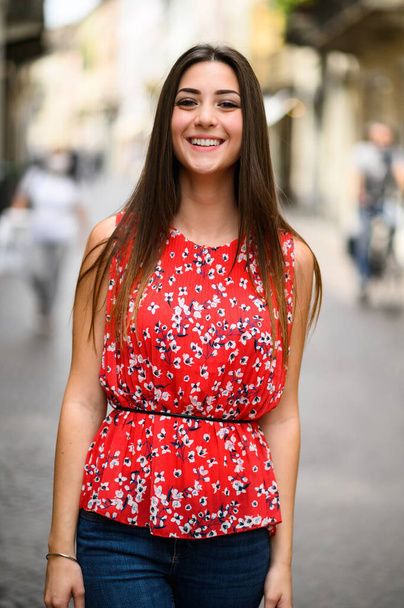 Beautiful charming young lady waking in a city street and looking back at the camera - Foto, Imagem