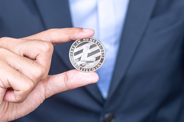 Liikemies käsi tilalla Silver Litecoin (LTC) kryptovaluutta, Crypto on digitaalista rahaa lohkoketju verkossa, vaihdetaan teknologian ja online-internet vaihto. Taloudellinen käsite - Valokuva, kuva