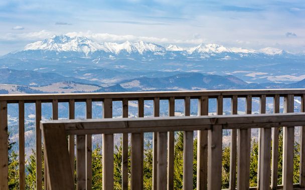 View of the Tatra mountain range from behind a wooden balustrade on an observation tower built on the Radziejowa peak in Beskid Sadecki. This peak is on the list of the Crown of Polish Mountains. - Photo, Image