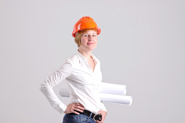 Archictress con casco de seguridad naranja y planes arquitectónicos
 - Foto, imagen