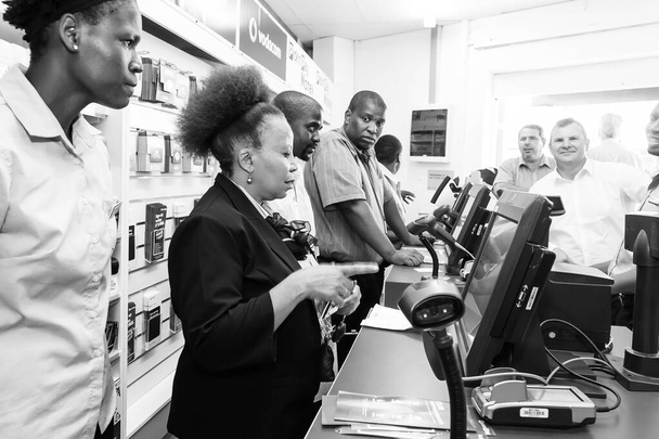 JOHANNESBURG, SOUTH AFRICA - Mar 13, 2021: Johannesburg, South Africa - October 27, 2016: African cashier and customer at checkout at local Pick n Pay grocery store - Foto, afbeelding