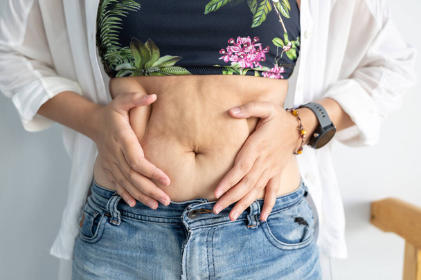Women body fat belly. Obese woman hand holding excessive belly fat. diet lifestyle concept to reduce belly and shape up healthy stomach muscle. - Foto, Imagem