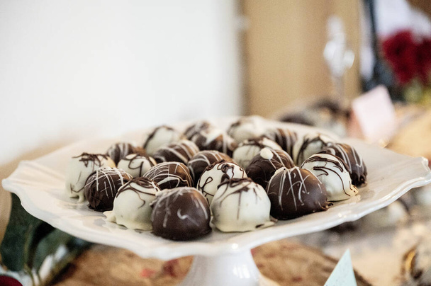 A closeup shot of candy balls made of white and dark chocolate - Фото, изображение