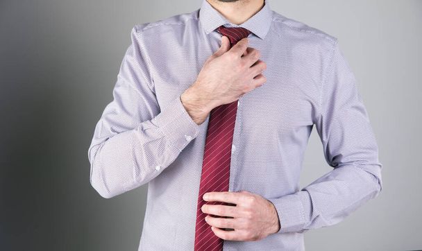 man straightens his tie on a gray background . - Foto, afbeelding