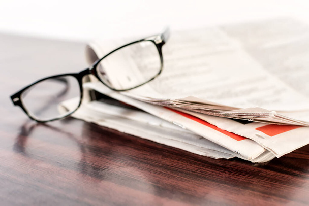 A closeup of newspapers and glasses on a wooden table - Foto, imagen