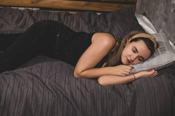 Młoda kobieta w luźnych ubraniach położyła się spać na łóżku. Koncepcja osób odzyskujących energię - Zdjęcie, obraz