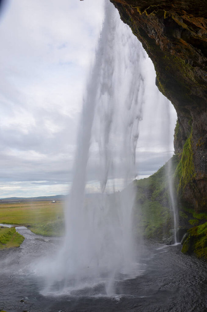 A vertical shot of a waterfall with green grass on the cliff and the plato - Foto, Imagen