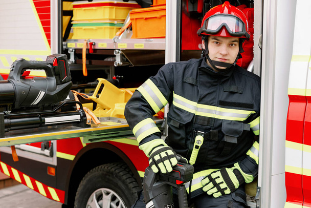 Un uomo di fisico forte in uniforme e casco sta vicino a un veicolo di soccorso. Uomo soccorritore - Foto, immagini