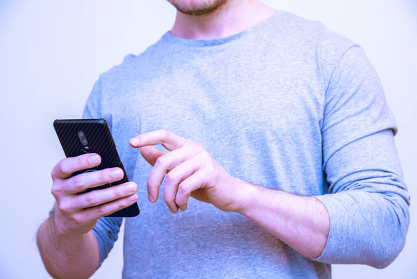 Ein flacher Fokus eines Mannes, der ein Smartphone isoliert auf weißem Hintergrund benutzt - Foto, Bild