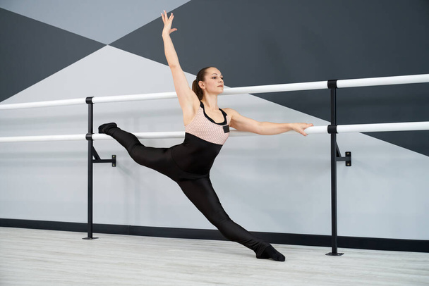 Woman stretching legs on handrails in dance studio. - Фото, зображення