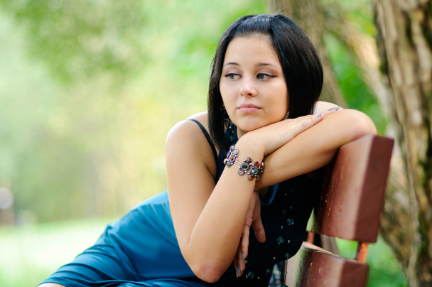 Pretty girl siiting on a bench in a park - Foto, afbeelding