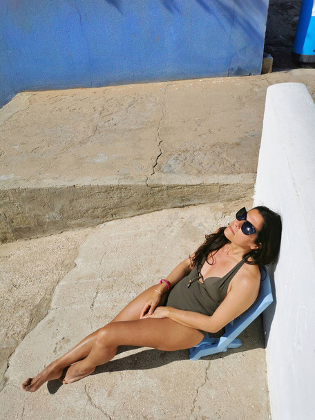 A vertical shot of a brunette middle-aged Hispanic female sunbathing and enjoying a beach day - Fotografie, Obrázek