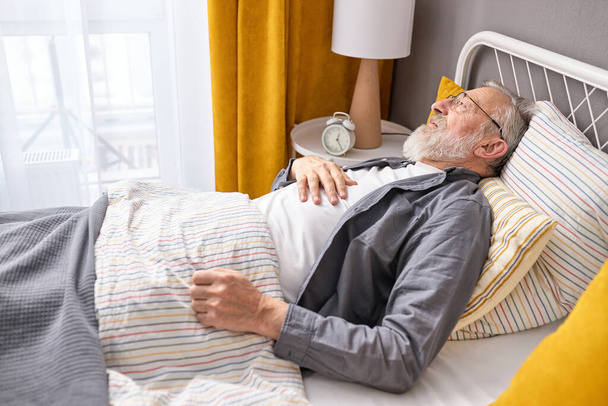 mature aged man ill, feel bad lying on bed at home alone - Foto, Imagem