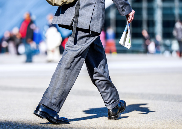 Business traveler man walking with newspaper in the street - 写真・画像
