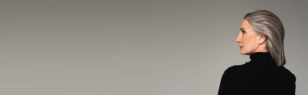 Sivunäkymä harmaa tukka nainen musta poolopaita eristetty harmaa, banneri - Valokuva, kuva