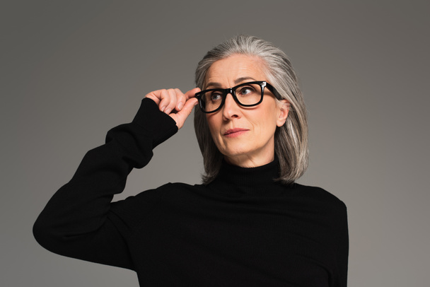 Mature woman holding eyeglasses isolated on grey  - Foto, Imagen