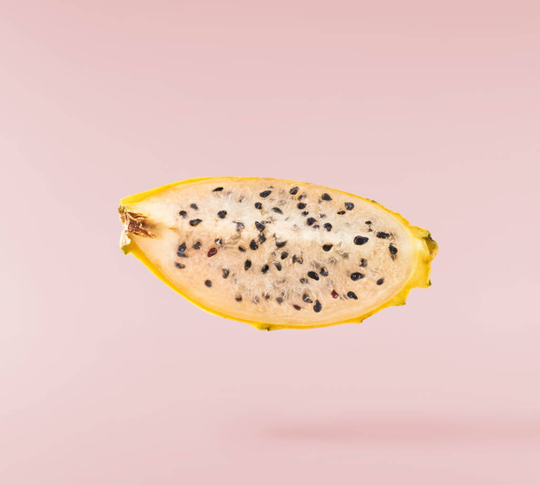 δημιουργική εικόνα με φρέσκα κίτρινα φρούτα δράκων ή pitaya που πέφτουν στον αέρα που απομονώνονται σε ροζ φόντο., αιώρηση ή μηδενικής βαρύτητας σύλληψη των τροφίμων. Εικόνα υψηλής ανάλυσης - Φωτογραφία, εικόνα