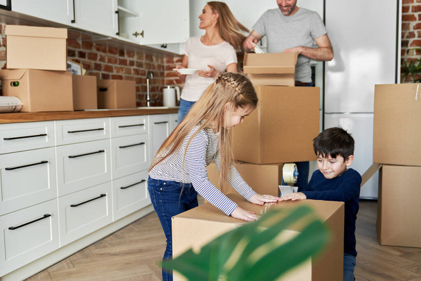 Siblings help with packing cardboard boxes for moving house - Fotó, kép
