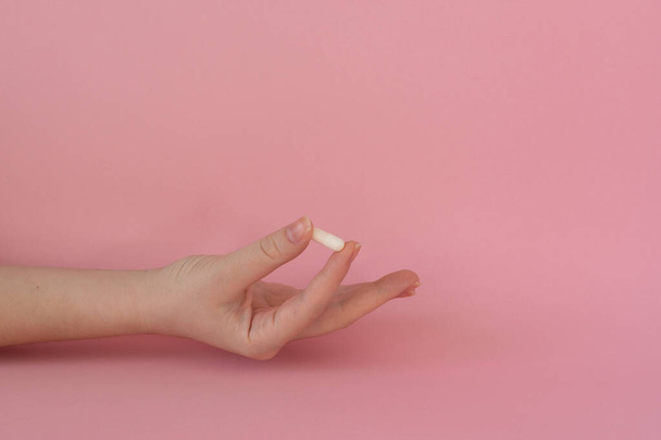 Comprimido en mano femenina, comprimido blanco, fondo rosa - Foto, imagen