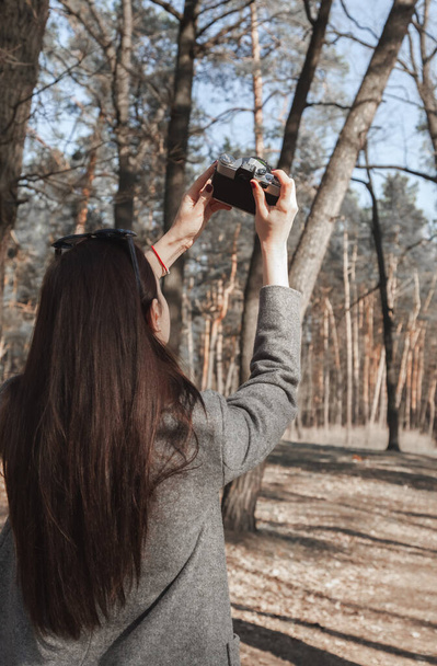 Doğayı ve ormanı eski, antika bir kamerayla fotoğraflayan bir kızın arka planı.. - Fotoğraf, Görsel