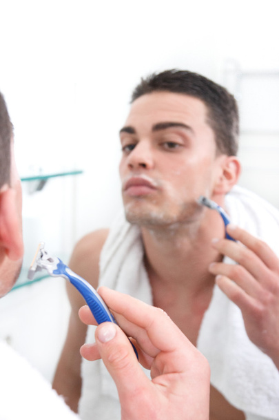 отражение молодого человека, бреющегося в зеркале ванной комнаты
 - Фото, изображение