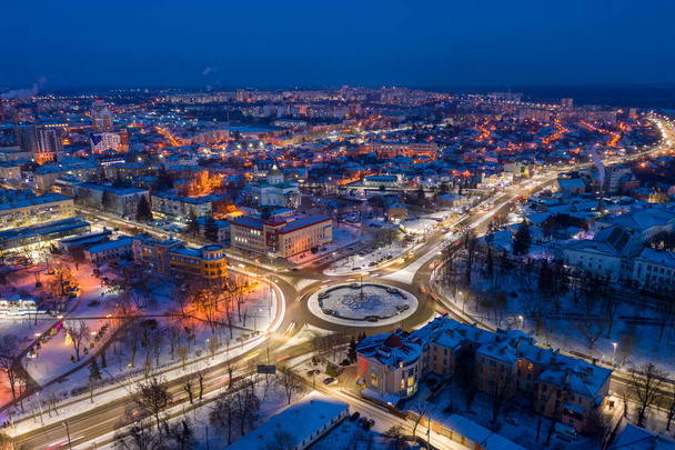 Piękny wieczorny widok na miasto. Wieczór, nocne oświetlenie w mieście. Zimowe miasto w śniegu. - Zdjęcie, obraz