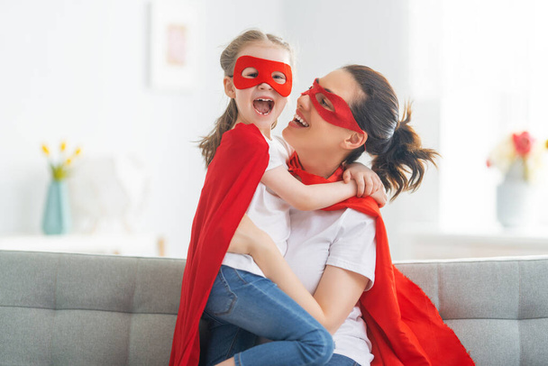 Mother and her child playing together. Girl and mom in Superhero costume. Mum and kid having fun. Family holiday and togetherness. - Fotoğraf, Görsel