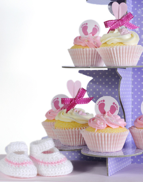 baby meisje cakejes en slofjes op paarse cupcake stand - Foto, afbeelding