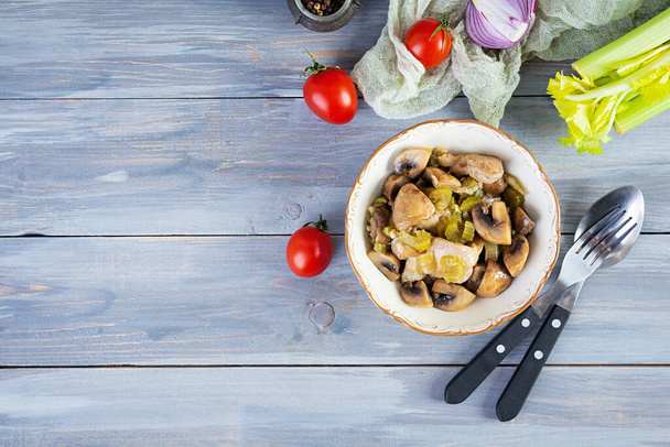 Faire cuire les cuisses de poulet avec les champignons, le céleri, l'oignon et le poivre. Mélanger le poulet frit sur fond en bois - Photo, image