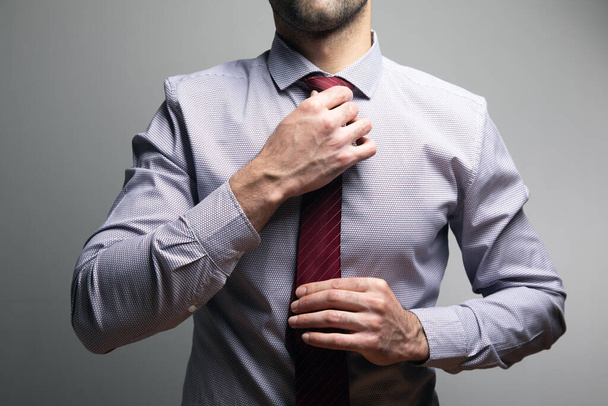 man straightens his tie on a gray background . - Fotoğraf, Görsel