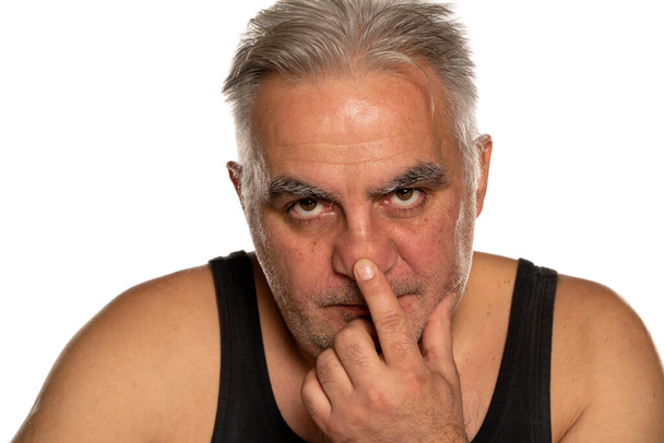 Занепокоєний чоловік середнього віку торкається свого носа на білому тлі
 - Фото, зображення