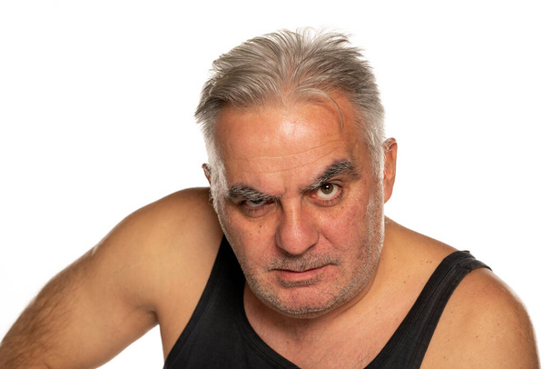 середнього віку злий чоловік з коротким сірим волоссям на білому тлі
 - Фото, зображення