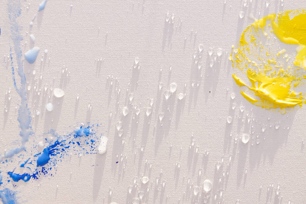 Blaue, gelbe und weiße Öl- und Acrylpinsel auf einer leeren Leinwand im Abendlicht. Künstlerischer Ausdruck und Malübungen im Freien, fern von zu Hause. - Foto, Bild