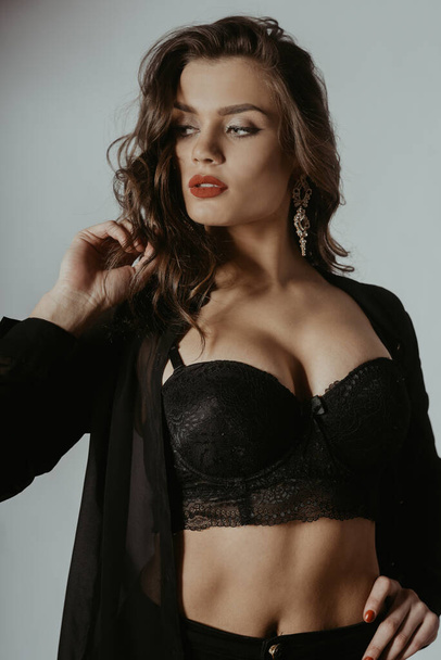 A beautiful photo of a girl in the studio in a dressing gown, pants and a top. Gorgeous girl with big breasts. Fashionable photo of a brunette with red lips. - Photo, Image