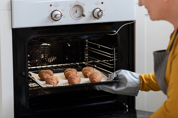 Nahaufnahme von Tablett mit hausgemachten Croissants Dame in den Ofen gelegt - Foto, Bild