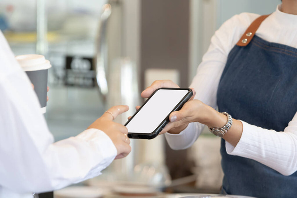 Owner or worker in cafe or restaurant  holding smartphone to customer. - Photo, image
