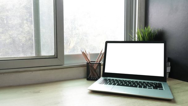 Ordenador portátil con pantalla blanca en blanco en el escritorio en el espacio de trabajo y el concepto de espacio de copia - Foto, Imagen