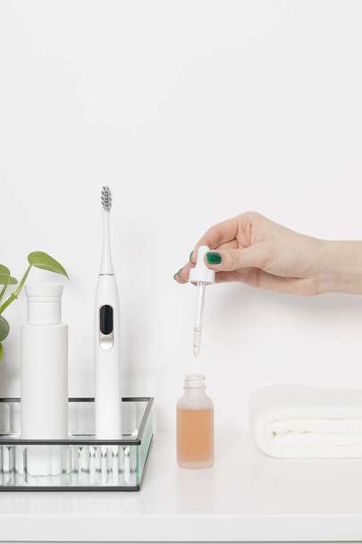 Woman holding pipette with serum in hand on a white background. Beauty treatment routine concept. - Fotó, kép